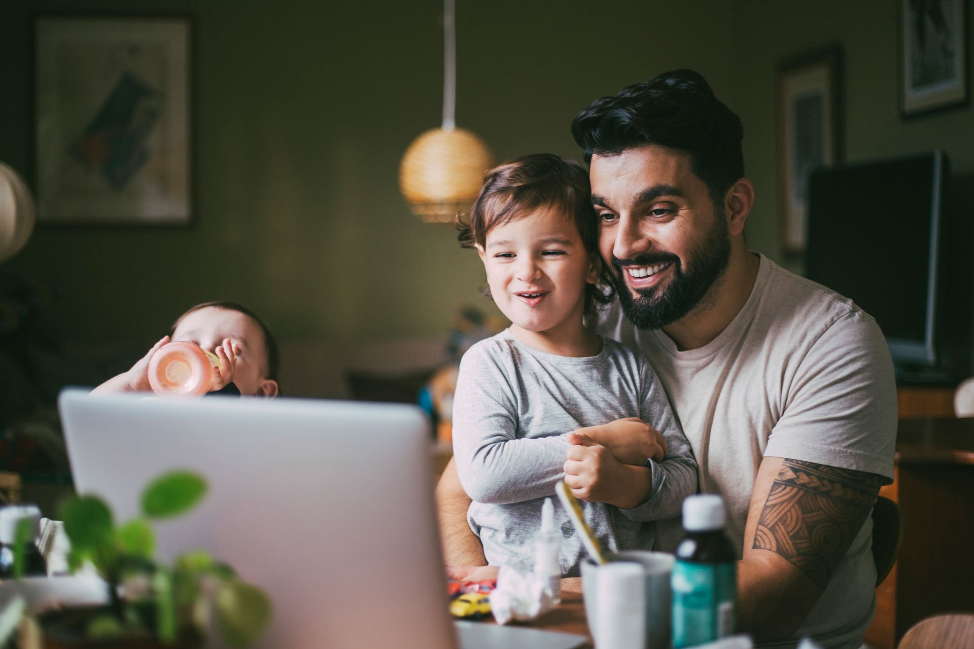 Barn och pappa sitter framför laptop och ser glada ut